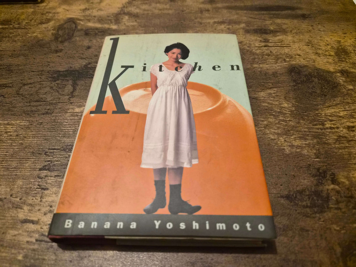 Banana Yoshimoto Kitchen first edition hardcover book cover featuring the title and author on a wooden table.