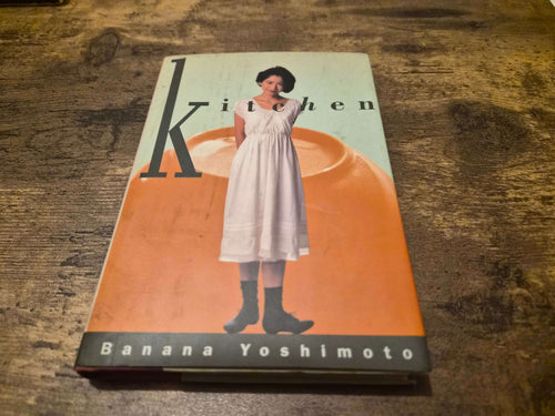 Banana Yoshimoto Kitchen first edition hardcover book cover featuring the title and author on a wooden table.